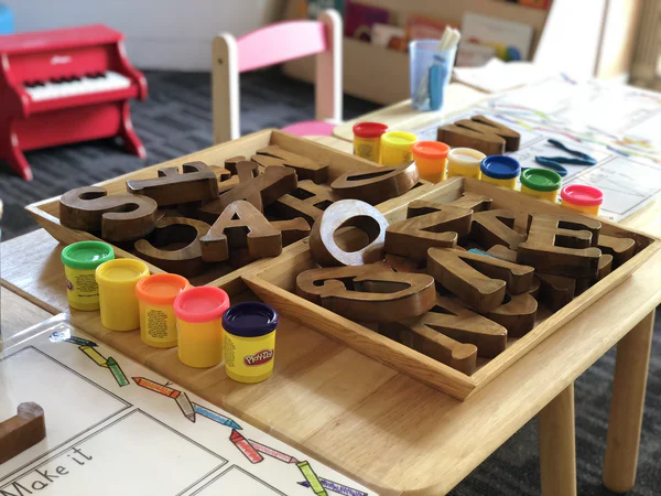 Daycare table of play dough and letters for children to play with. 