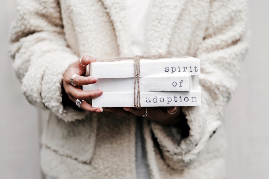 Woman holding books about the spirit of adoption wearing a heavy white sweater.