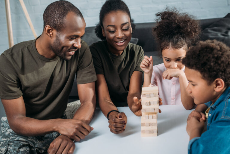 Black Family playing block game with children in the living room.