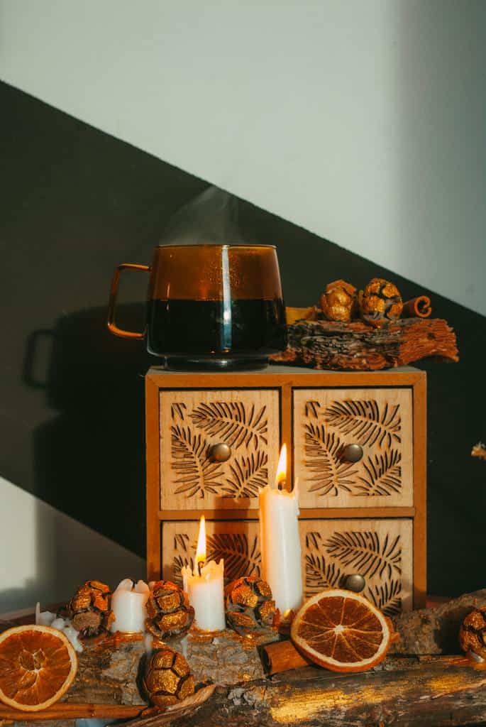 Holiday candles are lit before a wooden box with four shelves and dried fruit.